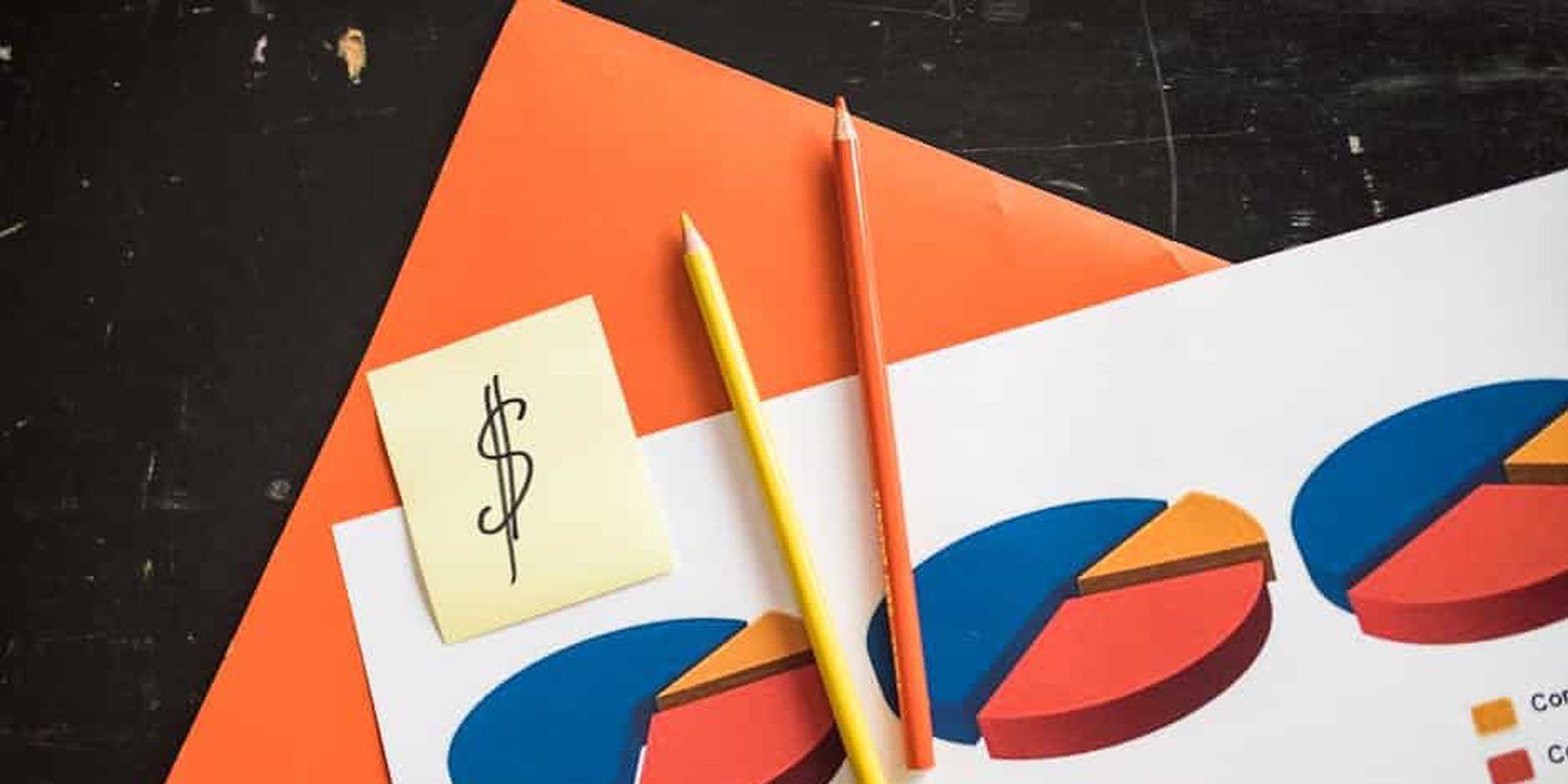 A creative arrangement of financial pie charts with colorful pencils and a dollar note, perfect for business themes.