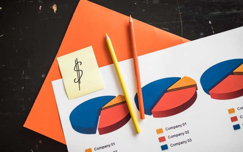 A creative arrangement of financial pie charts with colorful pencils and a dollar note, perfect for business themes.