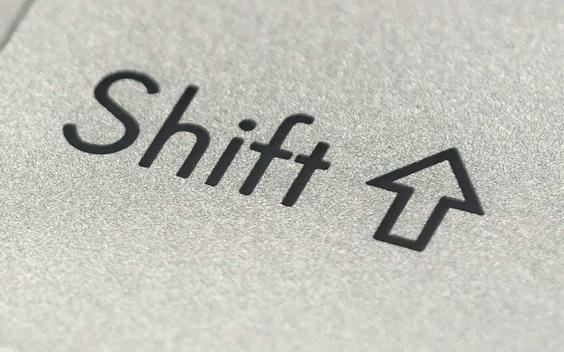 Macro photo of a silver keyboard shift key, showcasing detail and texture.