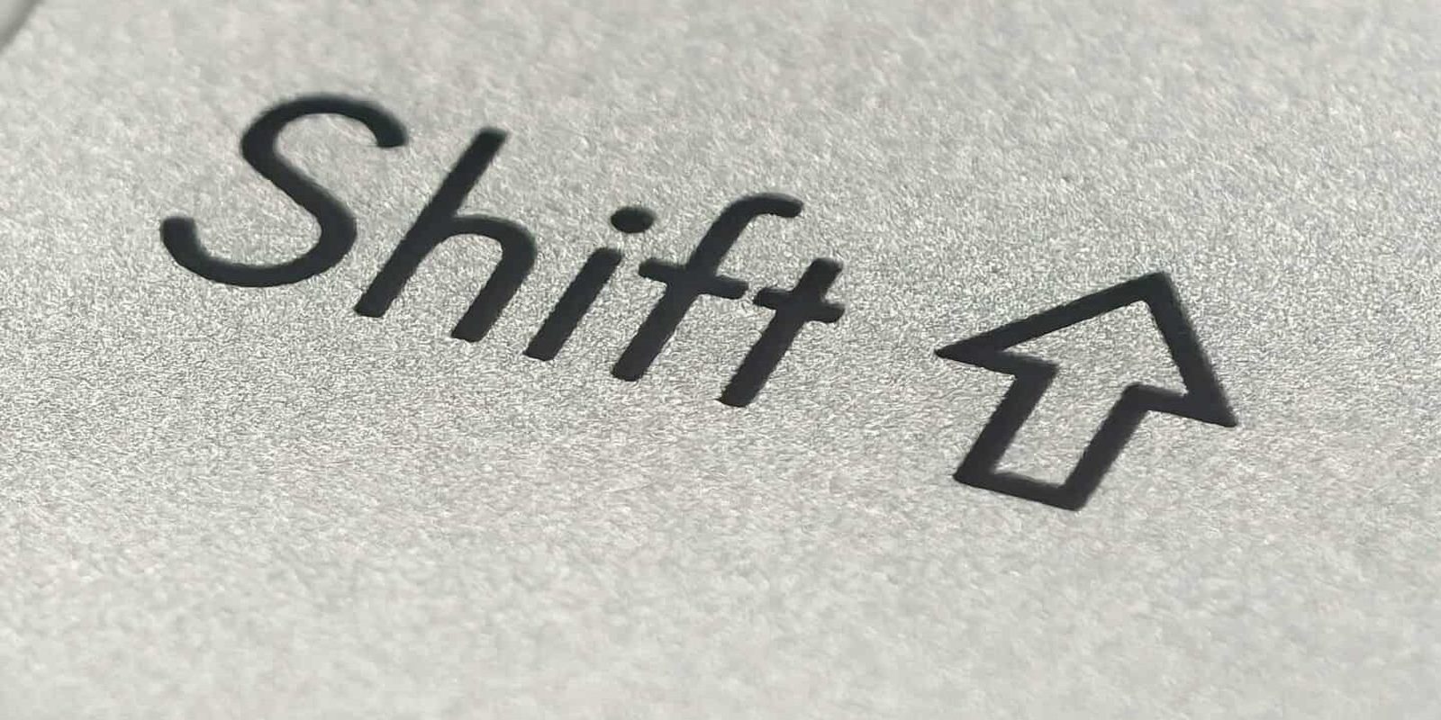 Macro photo of a silver keyboard shift key, showcasing detail and texture.