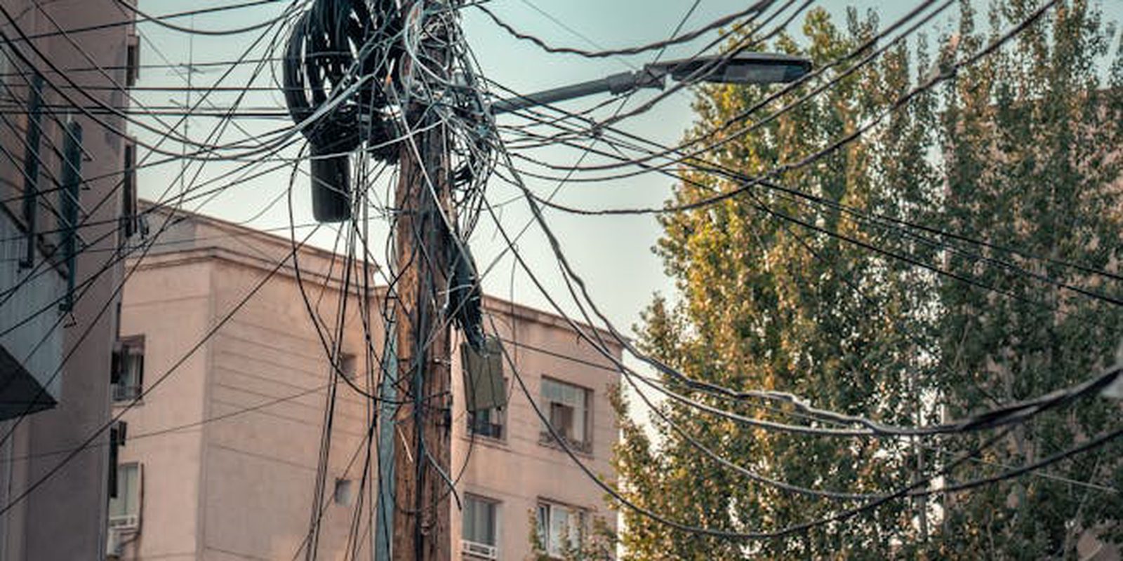 A messy web of power lines and cables on a street in București, Romania, showcasing urban infrastructure.