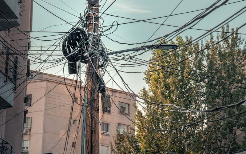 A messy web of power lines and cables on a street in București, Romania, showcasing urban infrastructure.