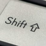 Macro photo of a silver keyboard shift key, showcasing detail and texture.